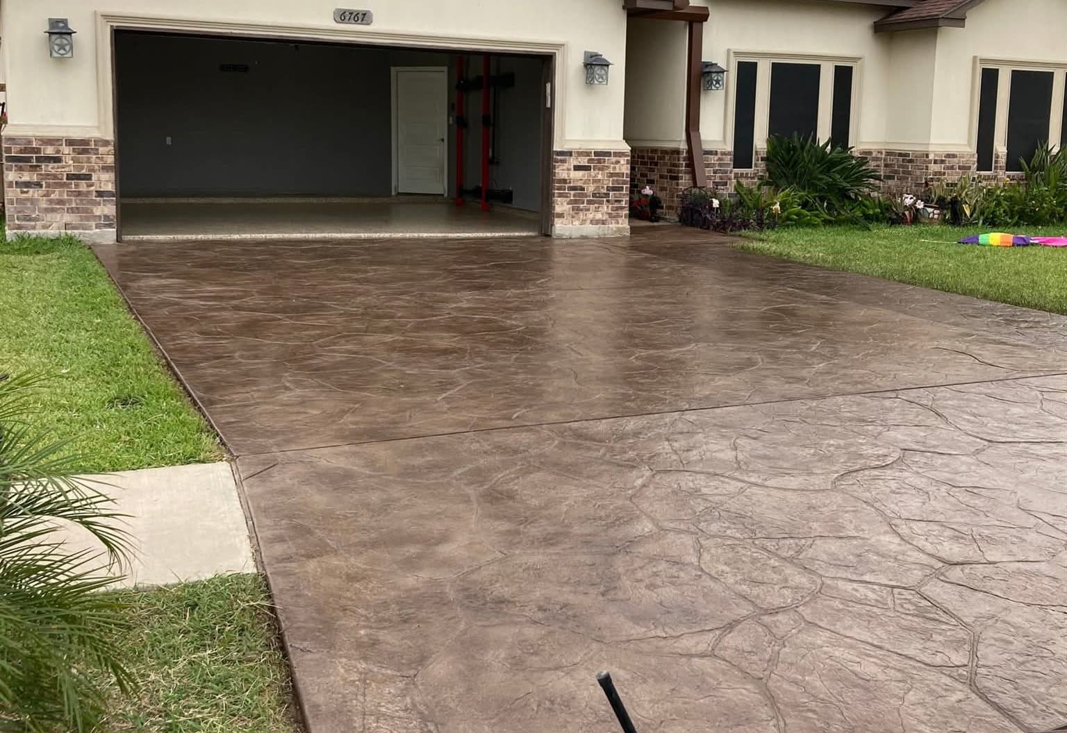 The same stamped concrete driveway after staining and sealing, in a warm brown finish.