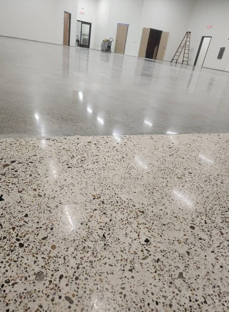 Polished concrete floor with exposed aggregate reflecting the lights of an open interior.