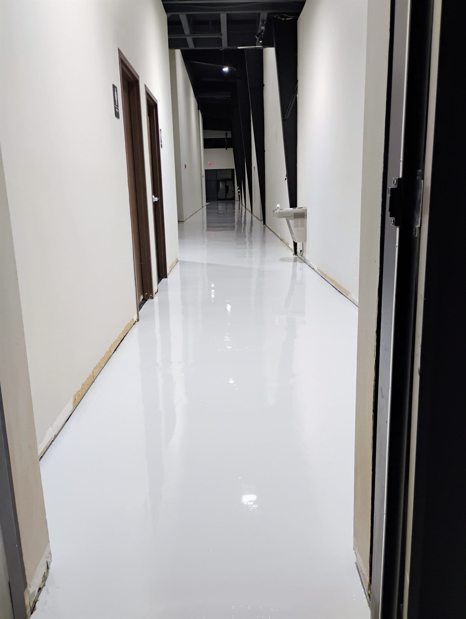High-gloss white floor coating running the length of a commercial corridor.