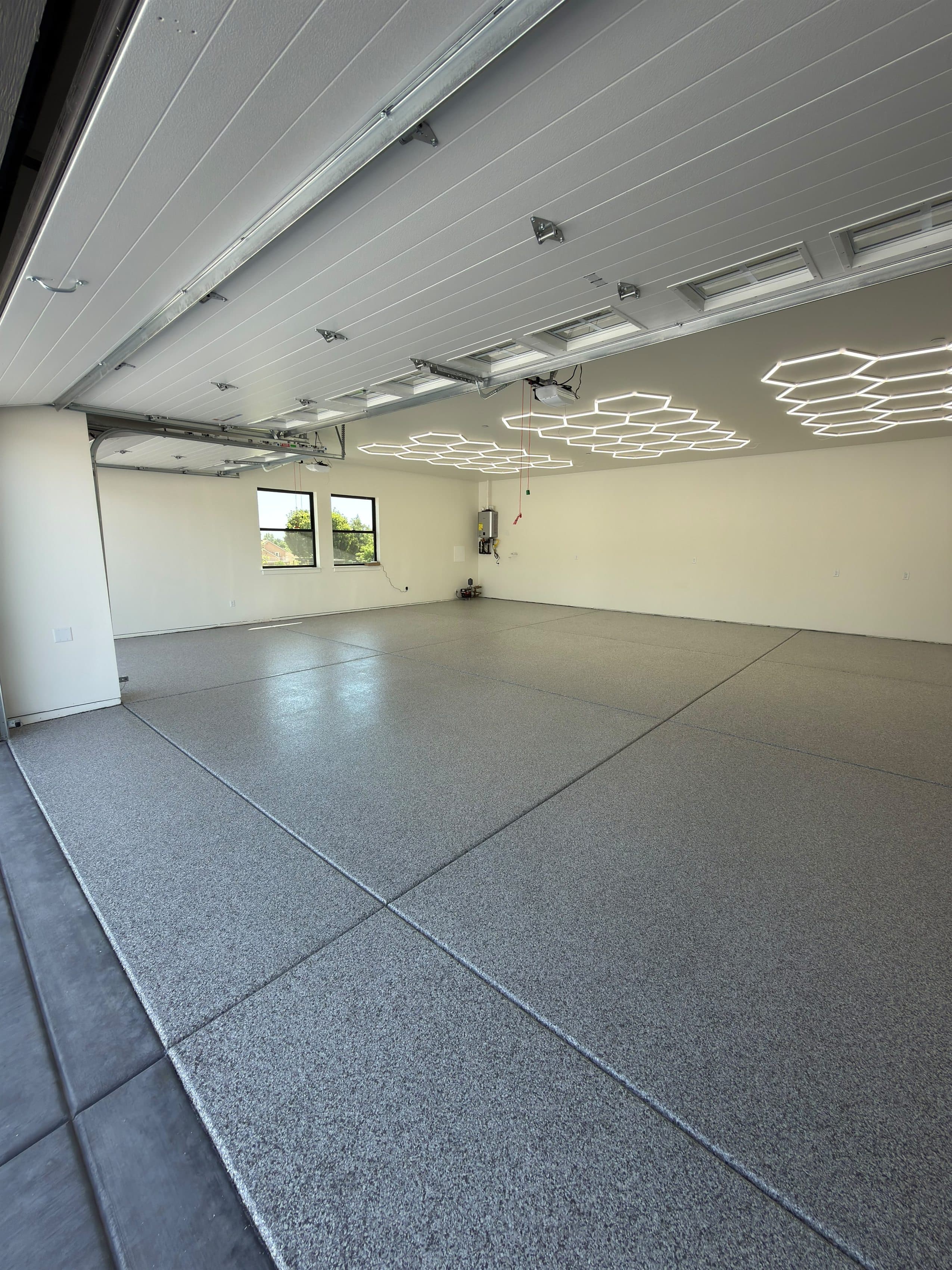 Grey flake epoxy floor covering the full slab of a large finished residential garage.